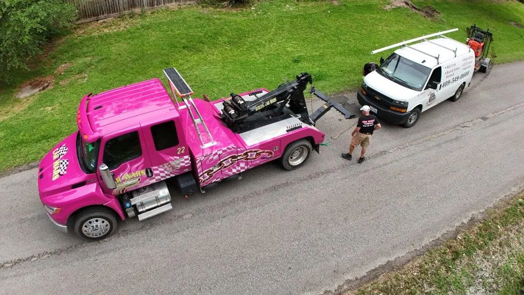 Pink Car Wars wrecker towing a white Honda CR-V in Orange, TX