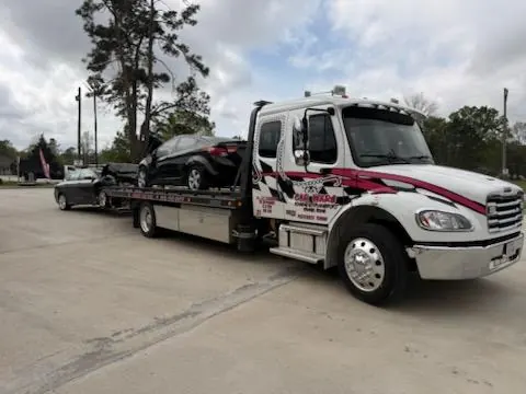 Pink Car Wars wrecker towing a commercial box truck at sunrise in Orange, TX